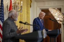 Foto: Donald Trump und Narendra Modi bei einer Pressekonferenz im Weißen Haus. Trump steht an einem Rednerpult und lächelt, Modi spricht.