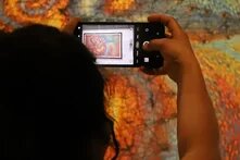 Foto: Person fotografiert ein buntes Kunstwerk mit dem Handy.